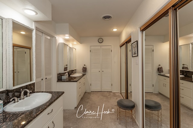 full bathroom featuring a closet, two vanities, a sink, and visible vents