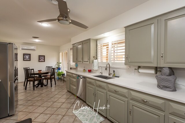 kitchen with light tile patterned floors, light countertops, appliances with stainless steel finishes, an AC wall unit, and a sink