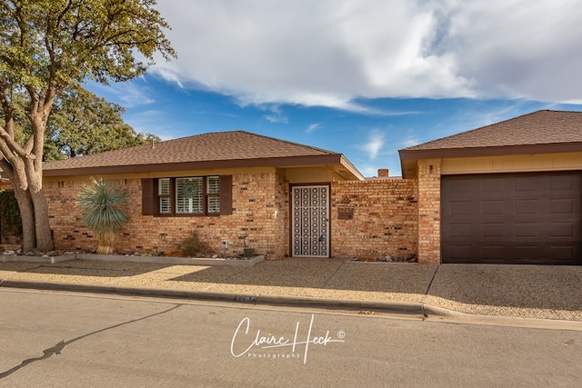 single story home with a gate, brick siding, and roof with shingles