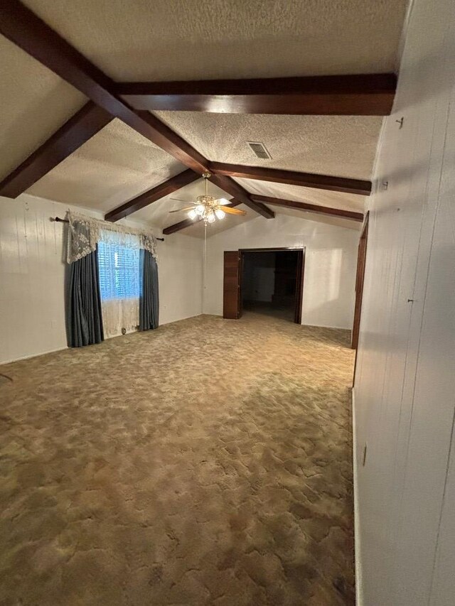 unfurnished living room with a textured ceiling, ceiling fan, lofted ceiling with beams, carpet floors, and wood walls