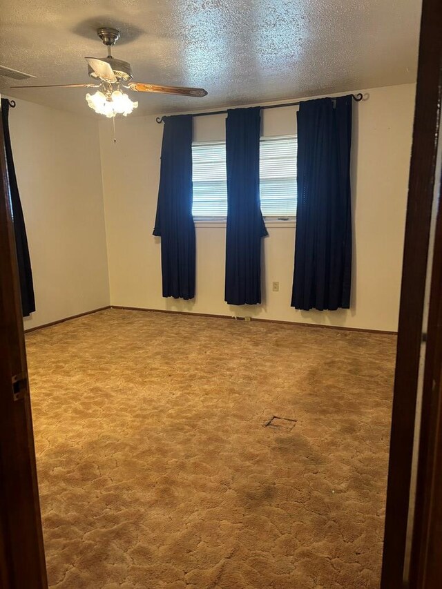 carpeted spare room with a textured ceiling and ceiling fan