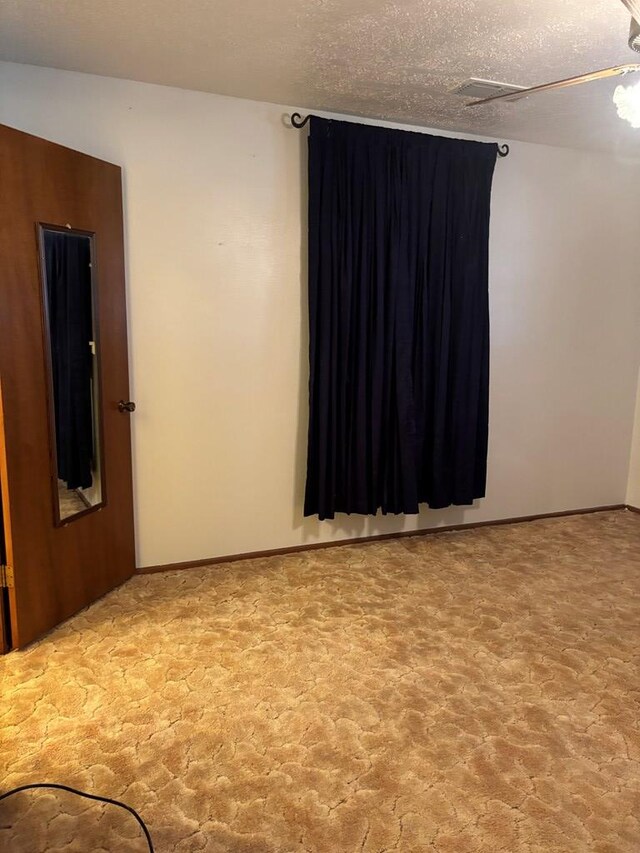 unfurnished room with carpet floors and a textured ceiling