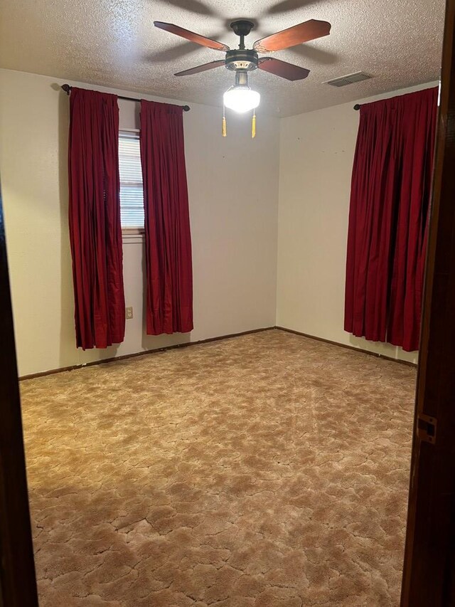 unfurnished room featuring a textured ceiling, carpet floors, and ceiling fan