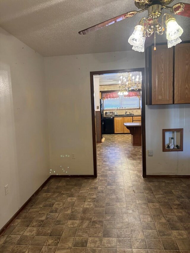 empty room with ceiling fan with notable chandelier, sink, and a textured ceiling