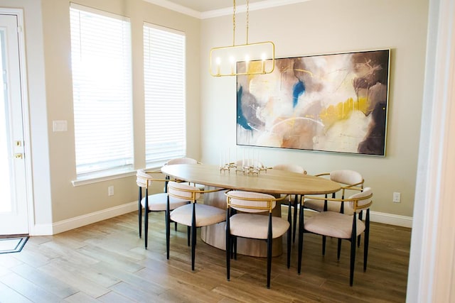 dining room featuring ornamental molding, a healthy amount of sunlight, a notable chandelier, and wood-type flooring