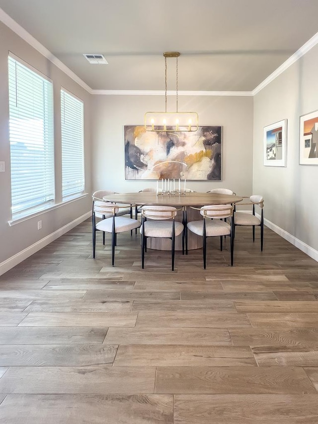 dining space with wood-type flooring, a notable chandelier, and ornamental molding