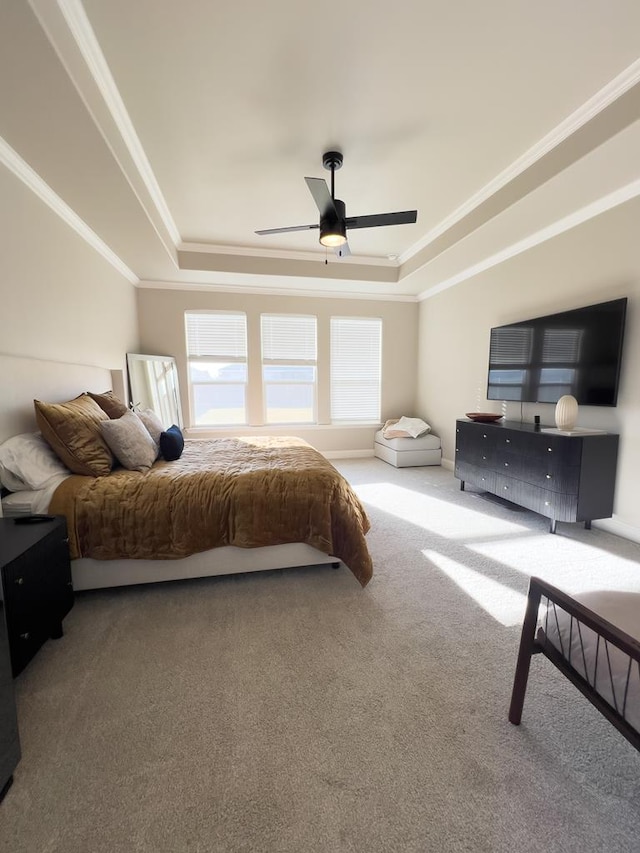 carpeted bedroom with a tray ceiling, ceiling fan, and crown molding