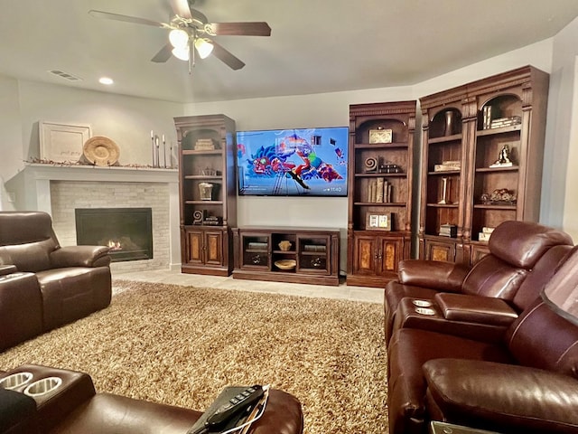 cinema room featuring ceiling fan, a fireplace, visible vents, and tile patterned flooring