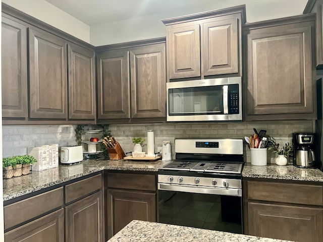 kitchen featuring light stone countertops, appliances with stainless steel finishes, decorative backsplash, and dark brown cabinets