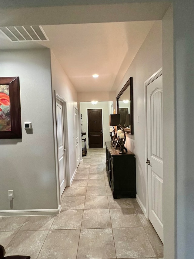 hallway with light tile patterned floors, baseboards, and visible vents