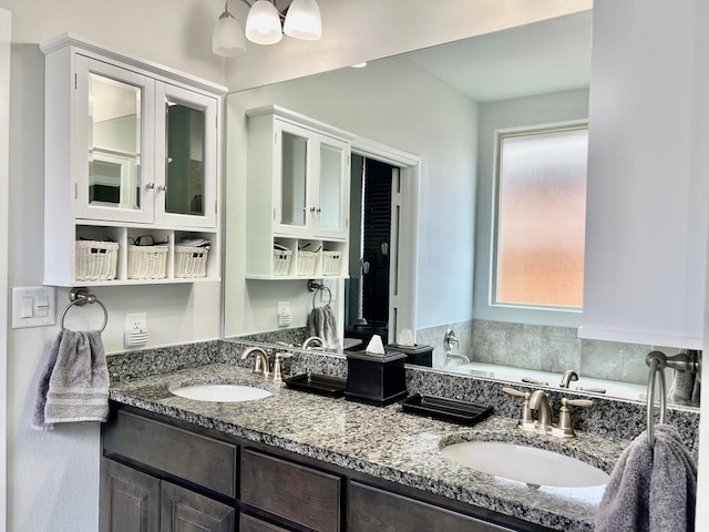 full bath with double vanity, a garden tub, and a sink