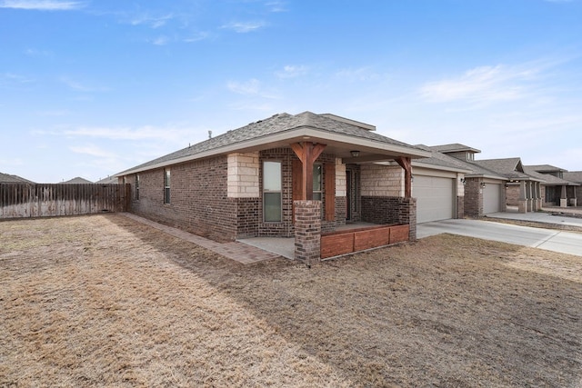 view of front of home featuring brick siding, covered porch, fence, a garage, and driveway