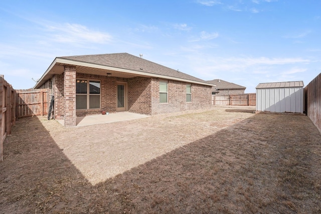 back of house with an outbuilding, a patio, brick siding, and a fenced backyard