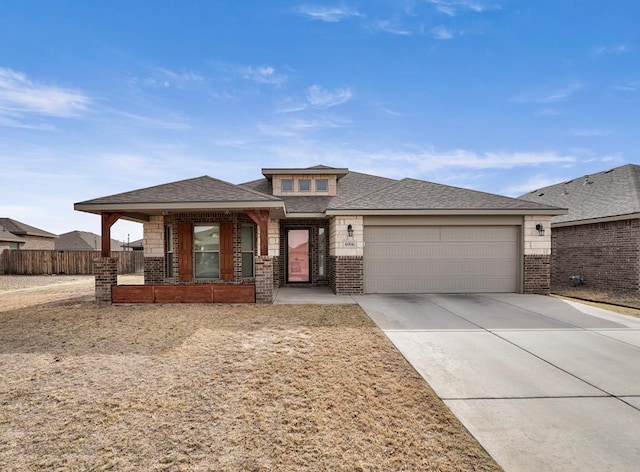 prairie-style house featuring brick siding, a shingled roof, an attached garage, fence, and driveway