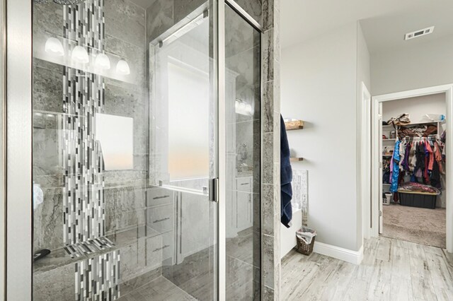 1706 Overshine Ln, Midland, TX 79705 - full bathroom featuring a walk in closet, a shower stall, and wood finished floors