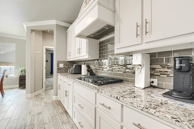 1706 Overshine Ln, Midland, TX 79705 - kitchen featuring premium range hood, stainless steel gas cooktop, tasteful backsplash, white cabinetry, and light stone counters