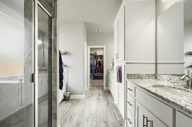 1706 Overshine Ln, Midland, TX 79705 - bathroom featuring vanity, a stall shower, a spacious closet, and wood finished floors