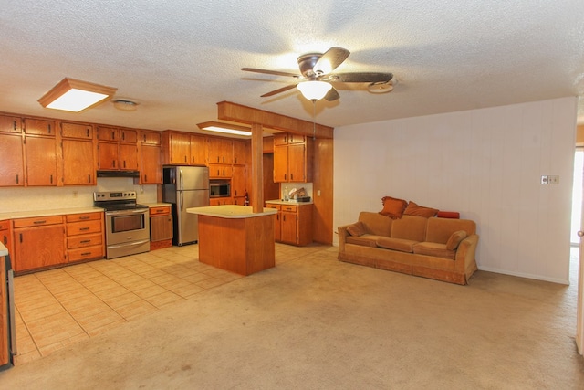 kitchen featuring a center island, ceiling fan, a textured ceiling, appliances with stainless steel finishes, and light colored carpet