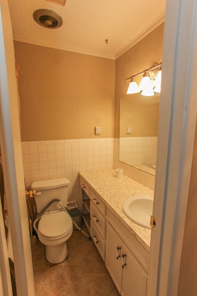 bathroom featuring tile patterned floors, a textured ceiling, toilet, tile walls, and ornamental molding