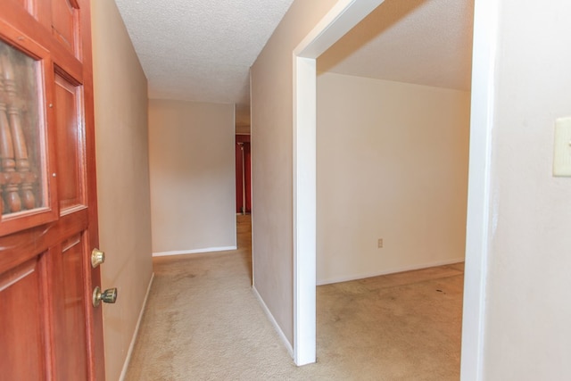 hall with a textured ceiling and light colored carpet