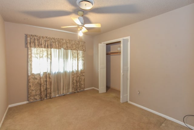 unfurnished bedroom with carpet, ceiling fan, a textured ceiling, and a closet