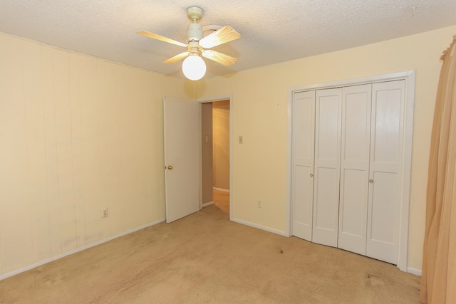 unfurnished bedroom featuring ceiling fan, a closet, light colored carpet, and a textured ceiling