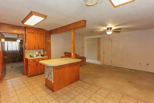 kitchen featuring kitchen peninsula, light carpet, wooden walls, and a textured ceiling