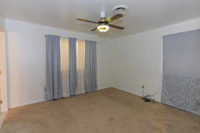 empty room with ceiling fan, light colored carpet, and ornamental molding