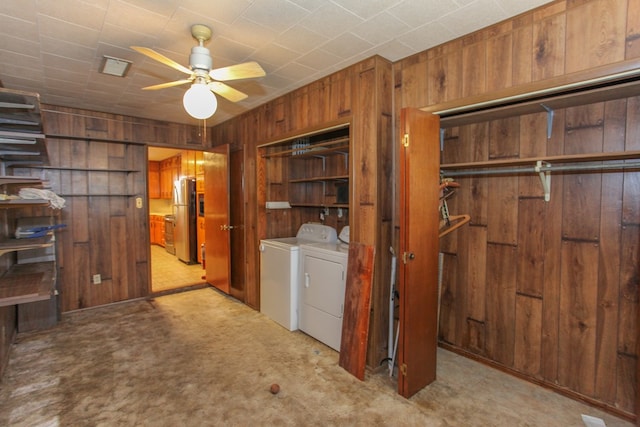 washroom featuring ceiling fan, wood walls, washing machine and dryer, and light colored carpet