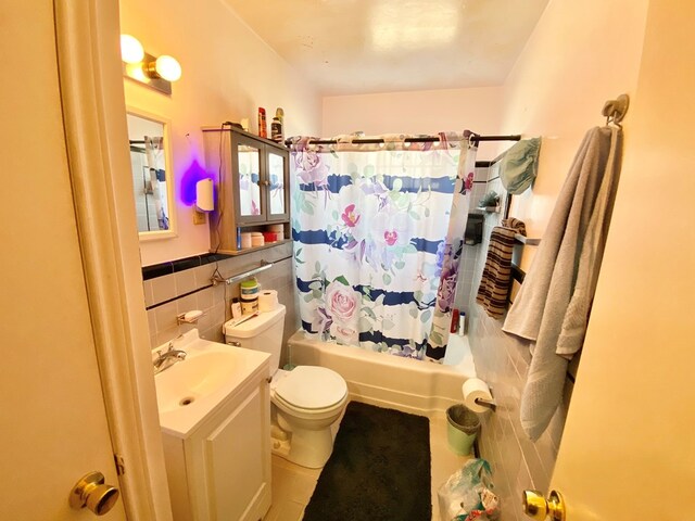 full bathroom with shower / bath combo, toilet, tile walls, and vanity