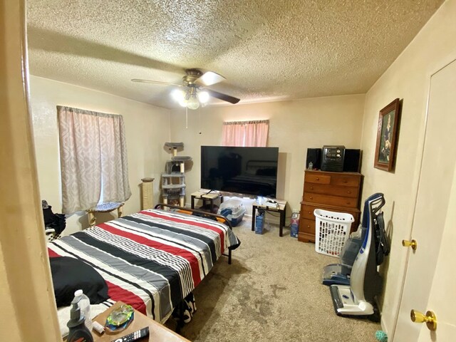 carpeted bedroom featuring ceiling fan and a textured ceiling