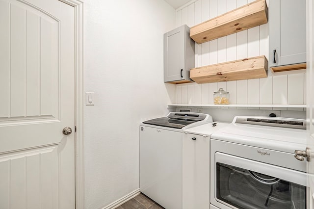 clothes washing area featuring cabinet space, washer and dryer, and wood finished floors