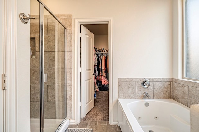 full bathroom with a walk in closet, a jetted tub, and a stall shower