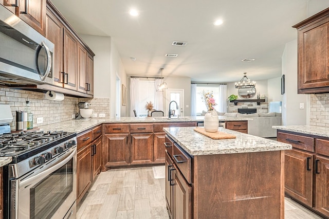 kitchen with visible vents, a sink, stainless steel appliances, backsplash, and a center island