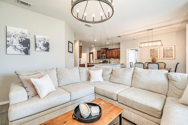 living room with a notable chandelier, visible vents, recessed lighting, and baseboards