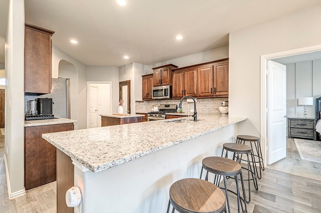 kitchen featuring a sink, a center island, stainless steel appliances, a peninsula, and a breakfast bar area