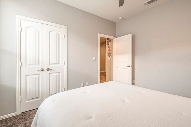 carpeted bedroom with a closet, visible vents, and a ceiling fan