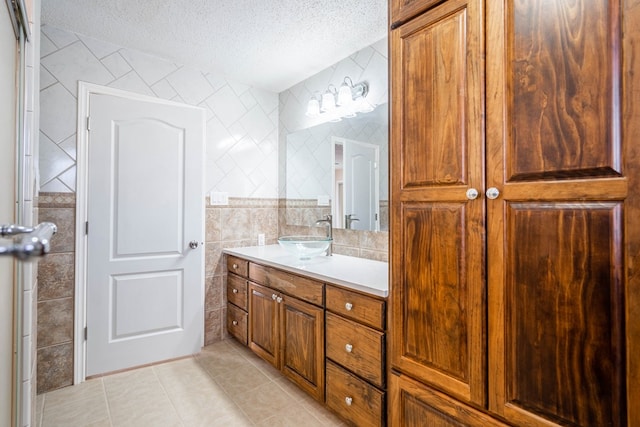 bathroom with tile patterned flooring, vanity, tile walls, and a textured ceiling