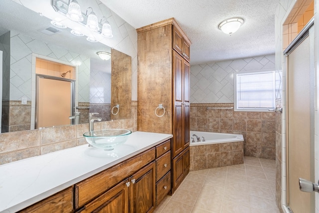 bathroom with tile walls, vanity, separate shower and tub, tile patterned floors, and a textured ceiling