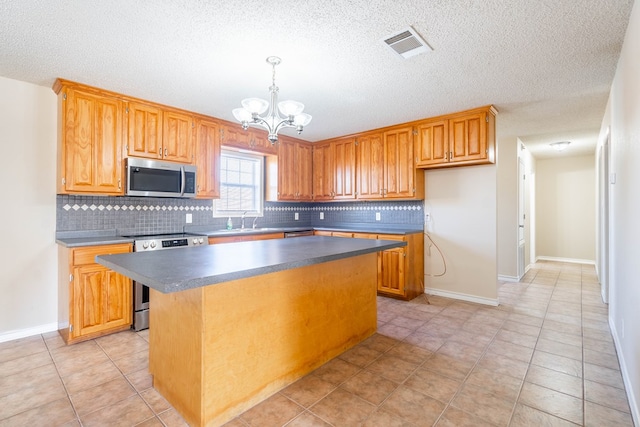 kitchen with appliances with stainless steel finishes, sink, backsplash, a chandelier, and a center island