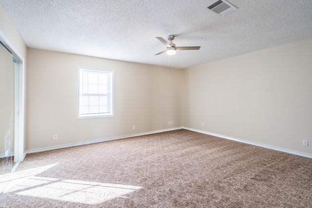 carpeted spare room featuring ceiling fan and a textured ceiling