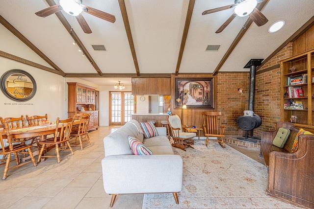 living room with vaulted ceiling with beams, a wood stove, ceiling fan, and visible vents