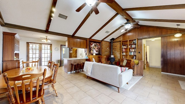 2701 S County Rd 1114, Midland, TX 79706 - living area featuring visible vents, a wood stove, ceiling fan, wooden walls, and vaulted ceiling with beams