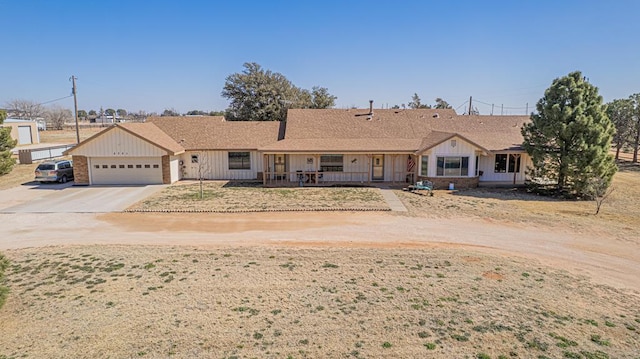 ranch-style house featuring board and batten siding, covered porch, driveway, and an attached garage