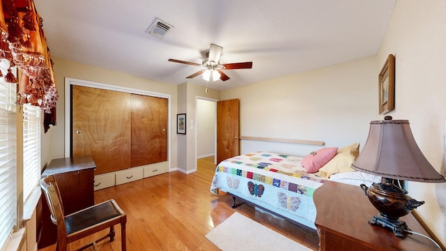 bedroom with ceiling fan, light wood-style flooring, visible vents, baseboards, and a closet