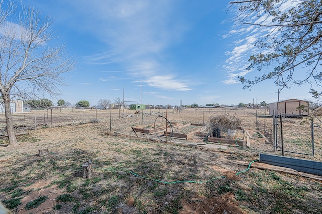 view of yard with a garden, fence, and a rural view