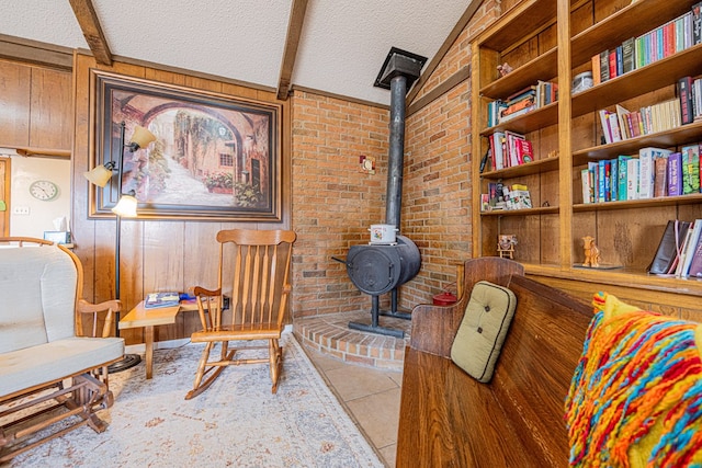 living area with a textured ceiling, brick wall, light tile patterned floors, and a wood stove