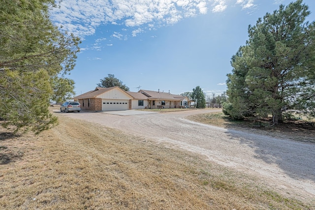 ranch-style home with an attached garage and dirt driveway