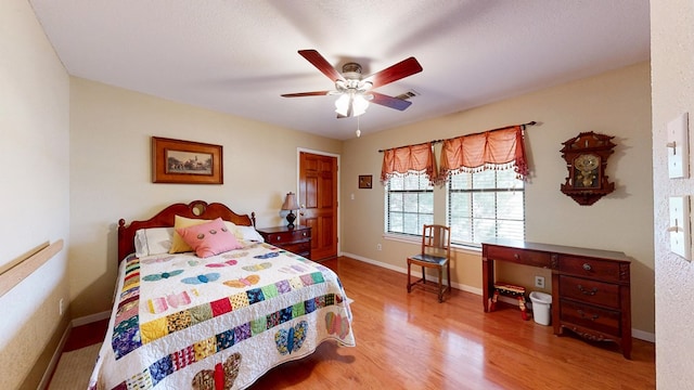 bedroom with light wood-style floors, visible vents, baseboards, and a ceiling fan