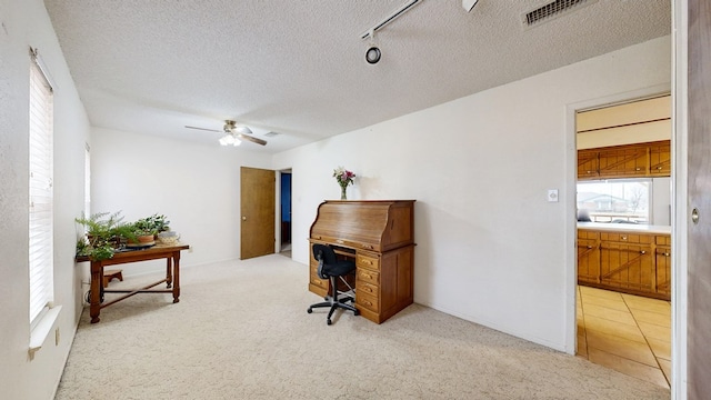 home office featuring light tile patterned floors, visible vents, a ceiling fan, light carpet, and a textured ceiling